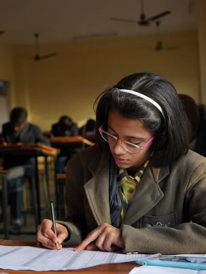 A student with glasses, focused intently on her paper, demonstrating the high level of concentration our training provides.
