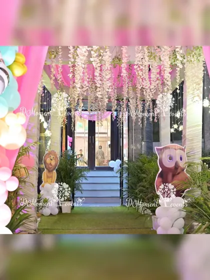 A beautiful entrance pathway for a jungle party, with hanging floral arrangements and animal cutouts peeking out from behind greenery.