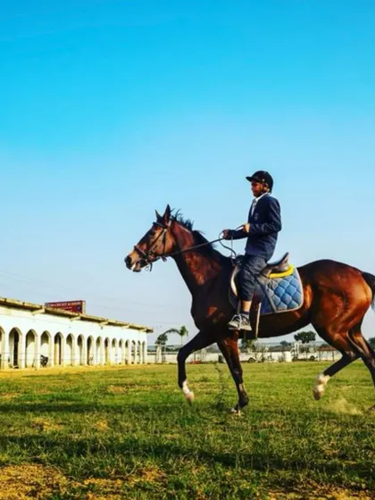 A young rider in full gear practices in our grassy field, demonstrating the elegant posture we teach at the academy.
