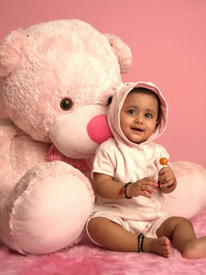A sweet baby poses with a giant pink teddy bear in our studio. This is the "before" shot for one of our AI transformations.