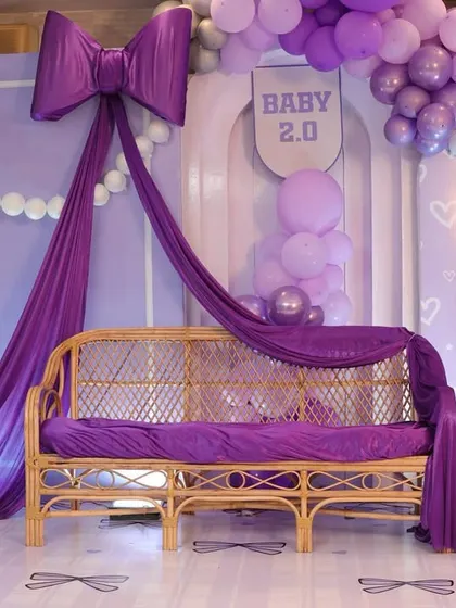 The elegant rattan bench draped in purple fabric, ready for the parents-to-be.