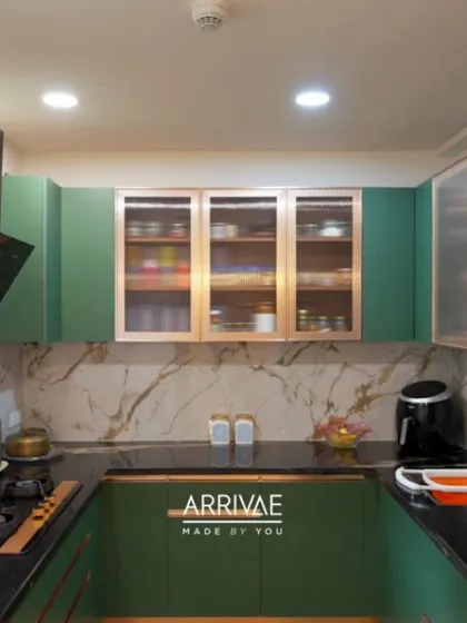 This U-shaped kitchen in a rich green is paired with a marble-veined backsplash and copper-framed glass cabinets, creating a look of sophisticated luxury.