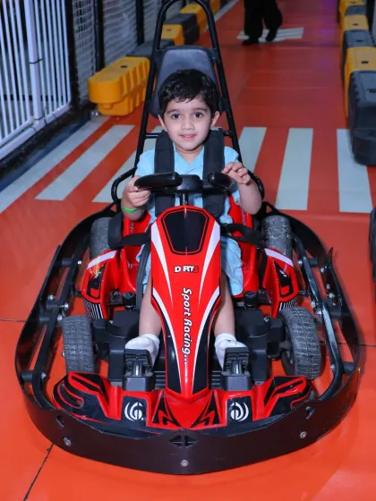 A happy driver gives a wave from his red sport racing go-kart before taking off on the track.