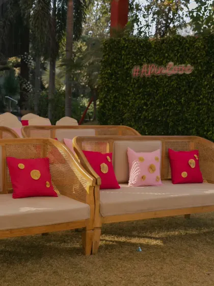 Chic and comfortable seating for a daytime Haldi event. The cane furniture is accented with bright pink cushions, adding a pop of color that complements the festive atmosphere.