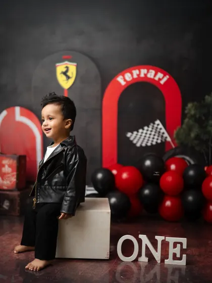 A candid moment of laughter during the Ferrari-themed first birthday session. The red and black color scheme creates a bold and exciting backdrop.