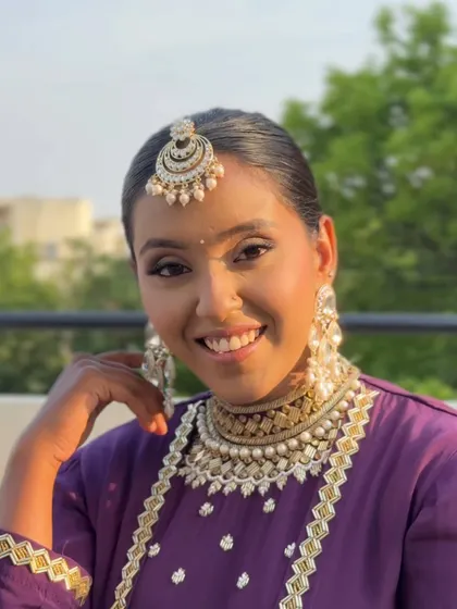 A joyful and vibrant look featuring soft pink and lilac eyeshadow. The makeup is fresh and youthful, perfectly complementing the purple outfit and heavy kundan jewelry.