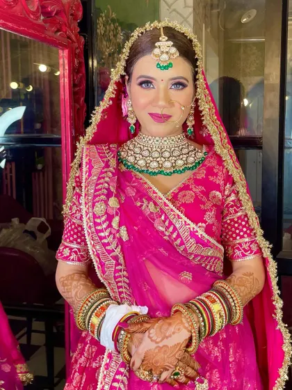 A stunning bride in pink. This look is all about radiance, with a glowing base and soft eye makeup that lets her beautiful green jewelry stand out.