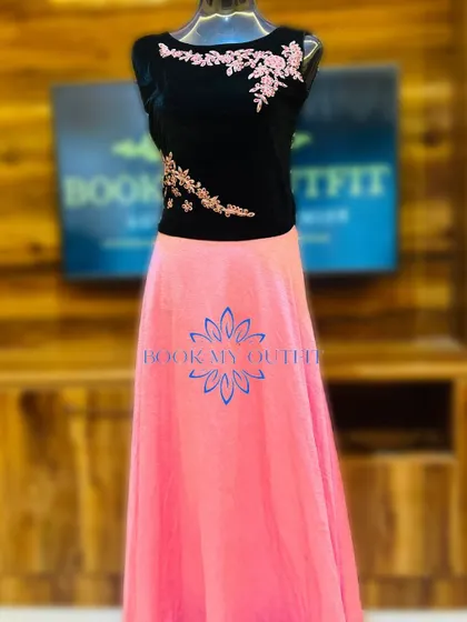 This two-piece style gown combines a black velvet top with delicate pink floral embroidery and a flowing pink skirt. It offers a modern and stylish take on the traditional long gown.