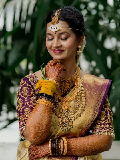 A beautiful South Indian bride in her traditional wedding attire. The portrait highlights the richness of her jewelry, the intricate embroidery of her blouse, and her joyful expression.