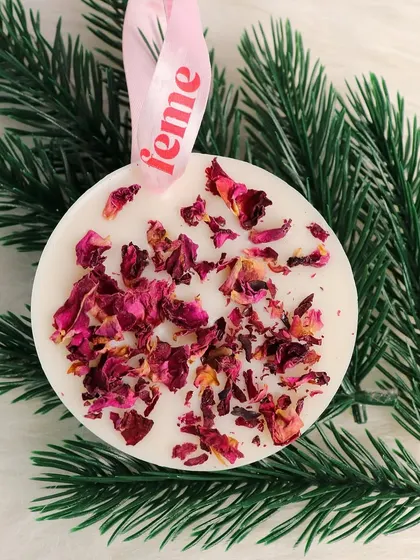 A wardrobe essential. Our rose petal wax sachet hanging on a pine branch, showing its versatility for festive decor.