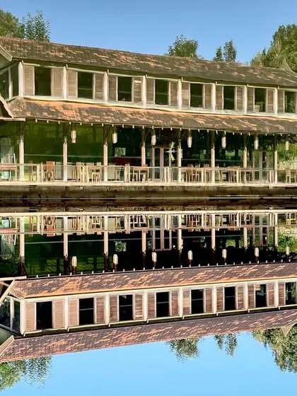 The ODEA' Riverside Retreat in Kotagiri, seen here with its perfect reflection. The structure is designed to be light on the land, using reclaimed railway sleepers and a modular metal frame for a sustainable and visually stunning result.