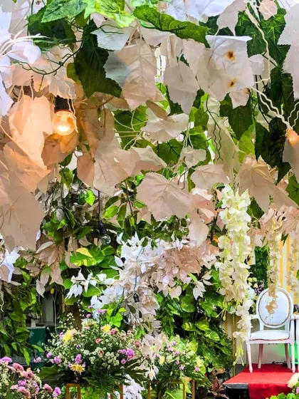 A beautiful wedding stage decorated with a lush wall of green and white leaves. This nature-inspired backdrop provides a fresh and elegant setting for the couple.