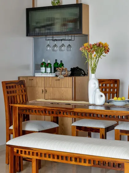 A close-up of a well-styled bar and dining area. Fresh flowers, colorful glassware, and a curated selection of drinks on a tray transform this functional corner into a beautiful feature for entertaining.