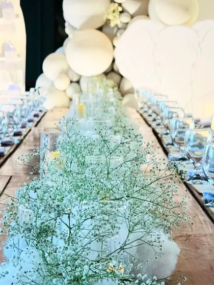 An exquisitely set dining table for a first birthday. The centerpiece is a runner of fluffy cotton and baby's breath, creating a dreamy, cloud-like effect.