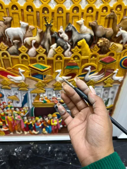 A shot showing my hand painting the fine details of the Samavasarana mural, giving a sense of the painstaking work involved in such a complex piece.