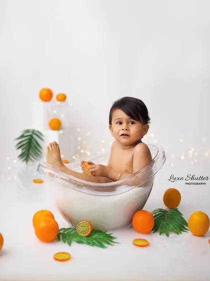 A baby boy sits in a miniature tub filled with milky water and oranges. This is a unique and playful idea for a sitter session.