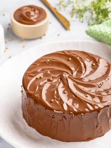 A classic chocolate cake, perfected. This one is coated in a thick, swirled layer of chocolate frosting and finished with delicate gold sprinkles for a simple, elegant look.