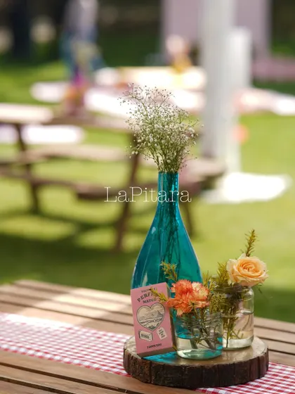 A beautiful centerpiece with a turquoise vase and a gingham table runner, creating a rustic-chic picnic vibe.