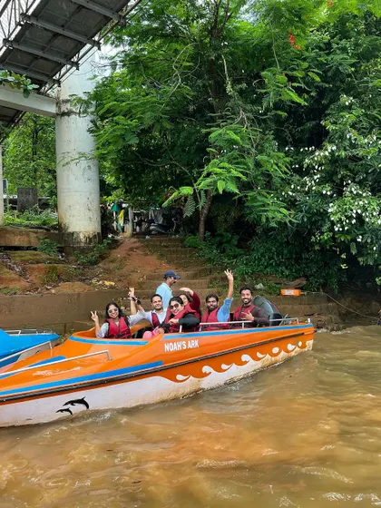 A group waving from a speedboat in Honnavara.