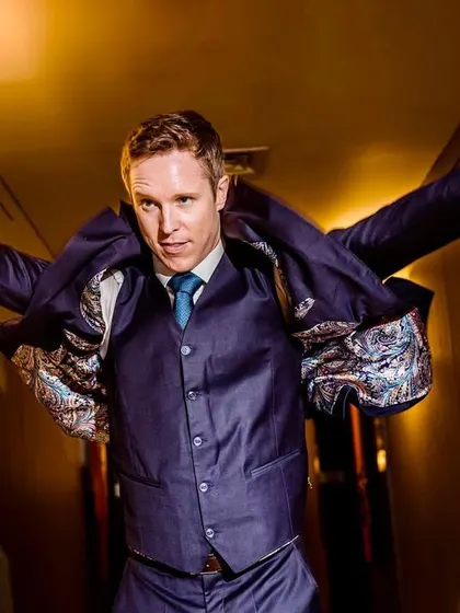 A fun, dynamic shot of the groom getting into his suit jacket. It has a 'superman' feel, capturing his energy and personality.