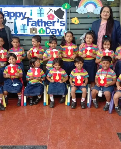 A class of preschoolers proudly holds up the tie-themed crafts they made for Father's Day, a day filled with love and creativity.
