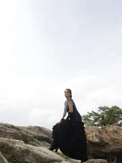 Part of a conceptual outdoor shoot, this look features a black ruffled skirt and embellished top set against a rocky, natural landscape. The styling was intended to create a dramatic, almost elemental fashion story.