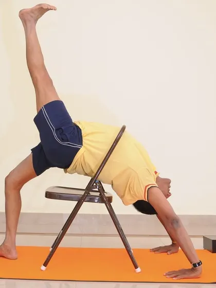 A variation of Adho Mukha Vrksasana (Handstand) using a chair. The chair supports the pelvis, allowing you to work on shoulder stability and spinal extension.