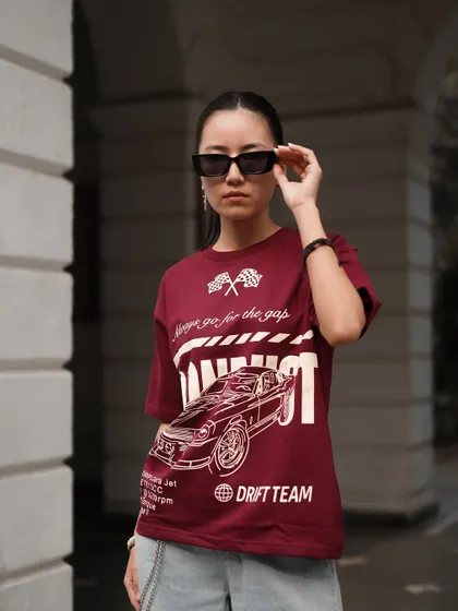 A closer shot to emphasize the graphic detail on the maroon t-shirt. The model adjusting her sunglasses adds a touch of action and personality, making the photo feel like a candid moment.