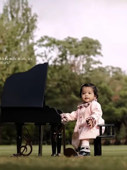 Raising kids is a walk in the park. Jurassic Park. A little girl in a pink coat at her piano in a vast green field.