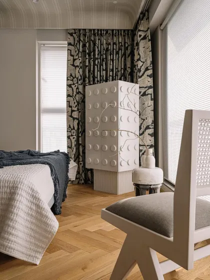 Another view of the master bedroom, showcasing the custom stone cabinet and bold patterned curtains. The mix of textures and forms creates a layered and interesting retreat.