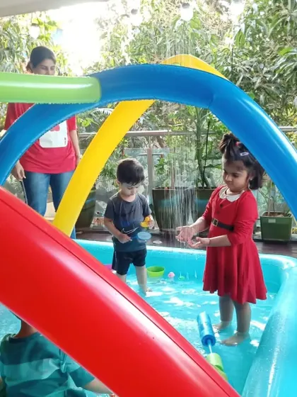 Our inflatable sprinkler arch adds another dimension to water fun. Here, two children are enjoying the gentle shower on a sunny day at the studio.