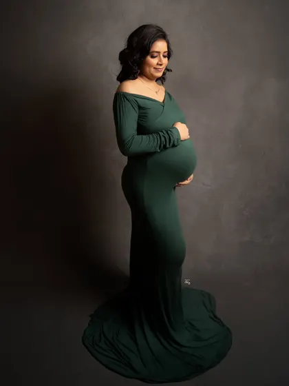 A side profile highlighting the beautiful curve of the baby bump. The simple elegance of the dark green gown makes this a truly timeless shot.