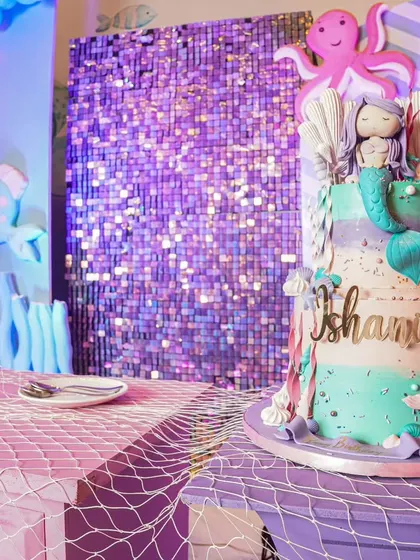 The stunning mermaid-themed birthday cake, featuring intricate details like shells, a mermaid tail, and an octopus, set against a shimmering sequin backdrop.