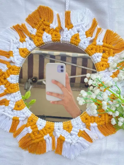 This boho macrame mirror features a fun, two-tone design in yellow and white. The alternating colors and fringed edges create a playful, sun-like effect that's sure to make you smile.