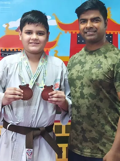 This young champion showcasing his two medals from the Open National Karate Championships. His hard work has truly paid off.