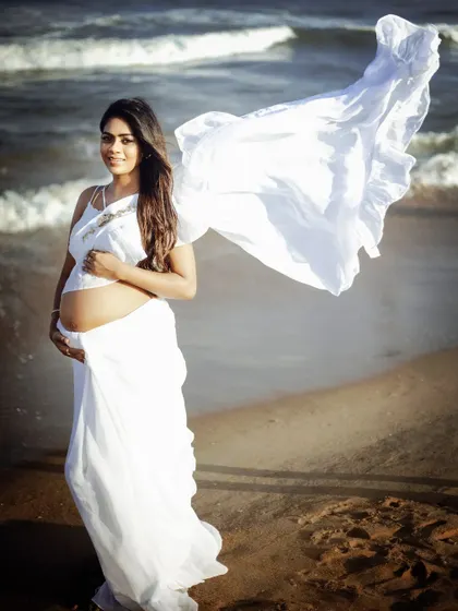 My custom white frill saree offers a unique and modern twist for a beach maternity shoot. The flowing fabric catches the ocean breeze perfectly, creating ethereal and memorable photographs.