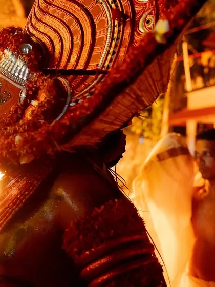 Close-up and action shots of the Kandanar Kelan Theyyam, focusing on the detailed costume, expressive mask, and the raw power of the fire performance.