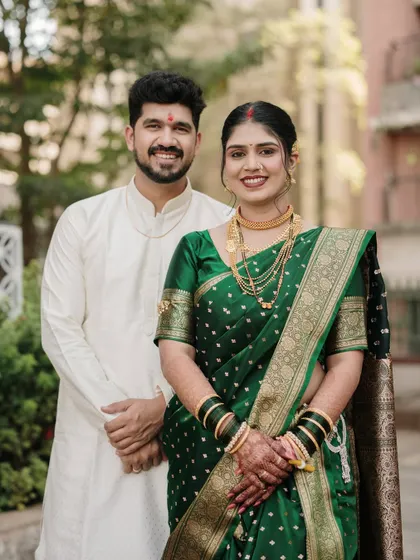 A classic portrait of the couple looking towards the camera, radiating happiness and elegance in their coordinated traditional green and white outfits.