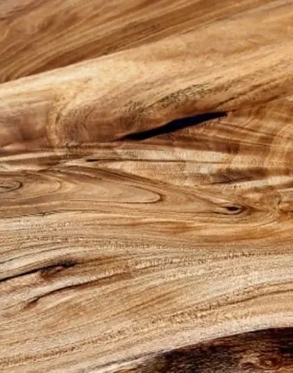 A close-up of the magnificent grain pattern in a slice of live-edge teak. The swirling lines and rich colors are nature's art, which I preserve in my tabletops.