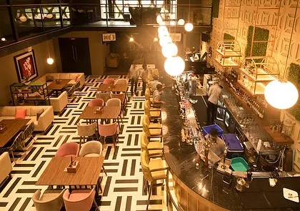 An overhead view of the bar and dining floor at Dank. The strategic placement of plants helps to define different zones and adds visual interest to the geometric floor pattern.