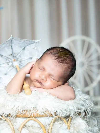This newborn is sleeping under a tiny lace umbrella, a delicate and charming touch.