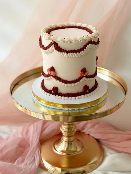A simple yet elegant cake with vintage-inspired piping in a deep red and white. This design showcases how classic techniques can create a modern look.