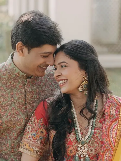 A sweet and happy moment between a couple during their wedding celebrations. Their bright smiles and gentle touch showcase the comfort and joy they find in each other.