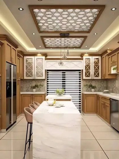 A luxurious, traditional kitchen with detailed wood cabinetry and an ornate ceiling design. The large central island with a marble top provides an additional workspace and seating area.