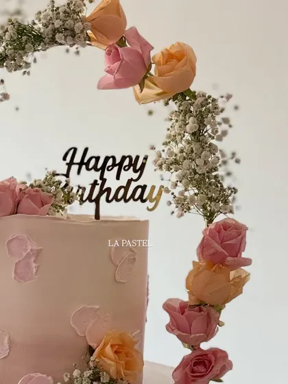 A close-up of the 'Happy Birthday' topper and the fresh roses on this elegant tiara cake.