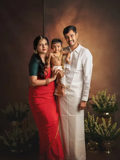 A classic family portrait with a traditional Krishna theme. The parents look on with love at their little one, creating a timeless and elegant family photograph.