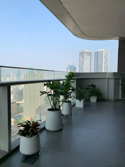 A wide view of the Omkar 1973 project, showing how a line of matching planters can create a sleek, uniform look on a modern curved balcony.