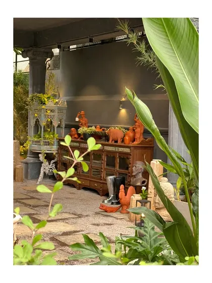 A glimpse into the eclectic and art-filled landscape designed for Peacock Life in Hyderabad. The space features a mix of antique furniture, colorful sculptures, and diverse planters.