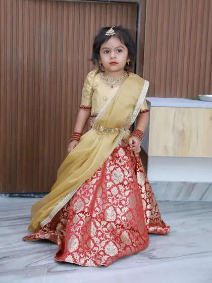 A little princess in a classic ensemble. This custom Langa Voni in red and gold brocade is a timeless choice for any festive occasion, designed to make your little one feel like royalty.