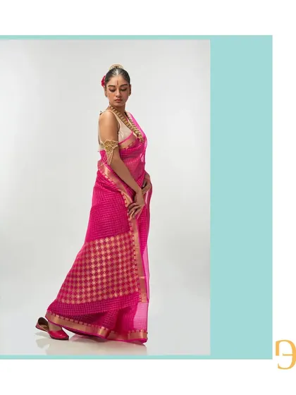 The vivid cerise organza saree in a dynamic pose, showing the beautiful movement and lightness of the fabric.